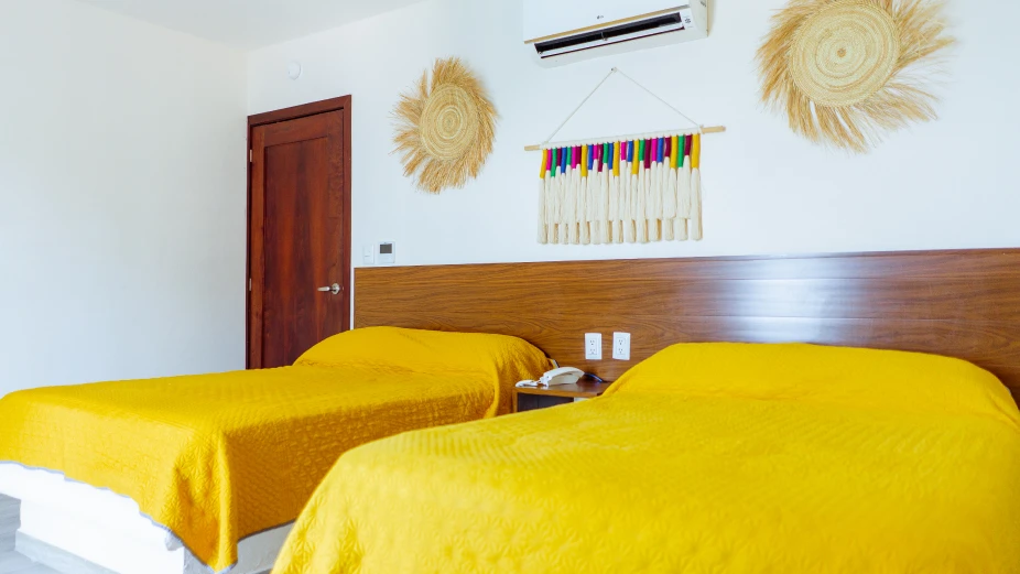 habitacion-con-dos-camas-con-aire-acondicionado-y-decoracion-en-la-pared