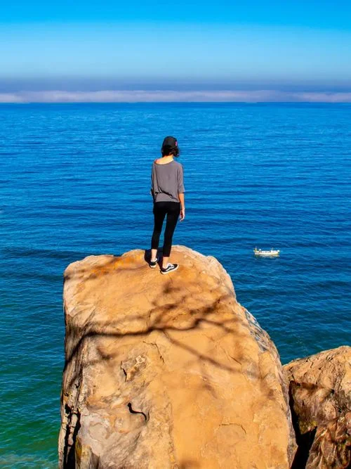 mujer-trepando-pierdras-frente-al-mar